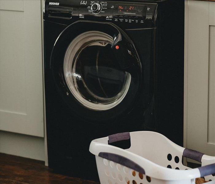 An under counter washer/dryer with laundry in a hamper 