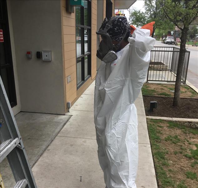 A SERVPRO technician wearing a tyvek suit and face mask for a bioremediation job