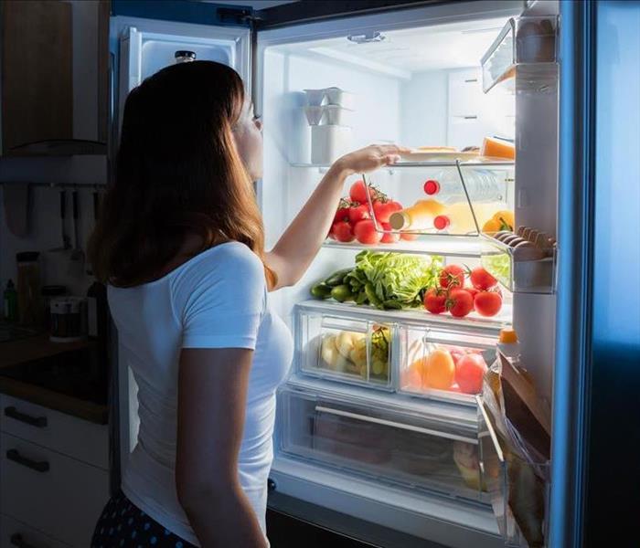 Woman Looking into stocked fridge